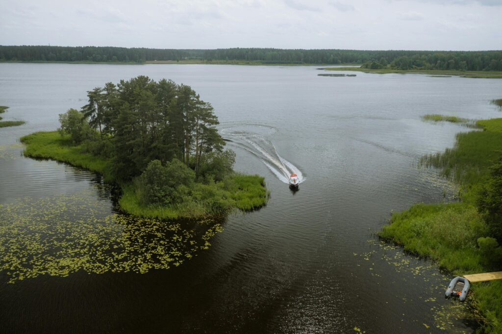 A serene aerial view of a boat navigating a lake in Tver Oblast, Russia, surrounded by lush greenery.